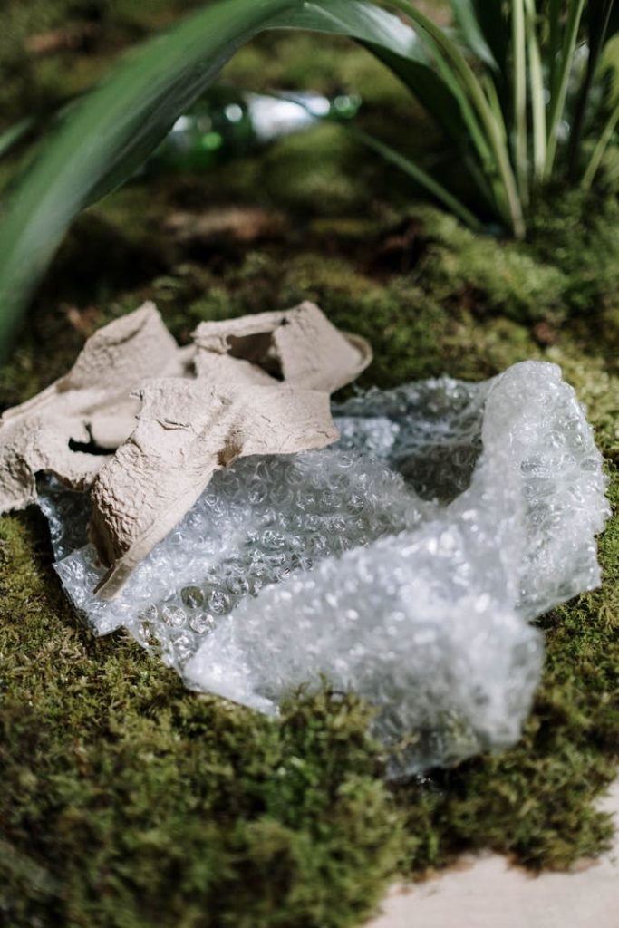 Bubble wrap and cardboard on moss symbolizes pollution challenges.